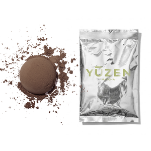 Hojicha sample in a silver foil sachet beside a pressed disc of brown roasted tea powder